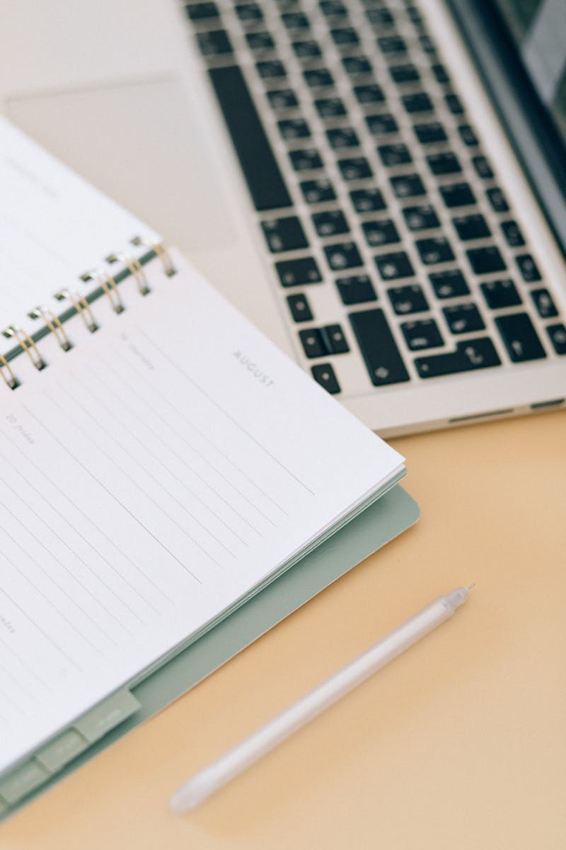 Open notebook next to a laptop and pen on a desk, ideal for business and planning.